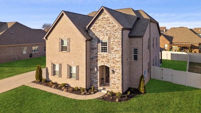 view of side of home with stone siding, brick siding, a lawn, and fence