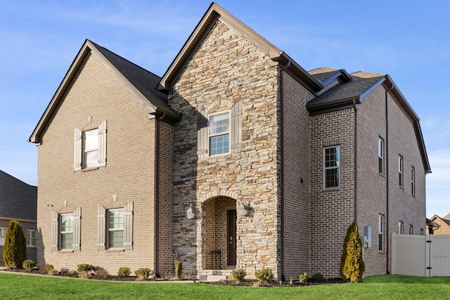 view of front of house with stone siding, brick siding, and a front yard