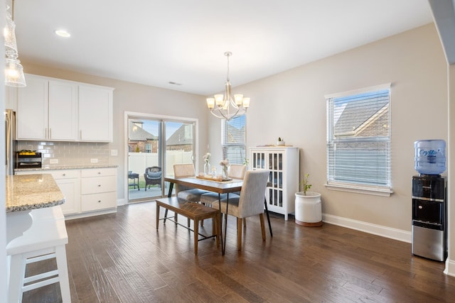 dining space with dark wood-style floors, visible vents, baseboards, and a chandelier