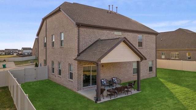 back of property featuring a lawn, a fenced backyard, roof with shingles, a patio area, and brick siding