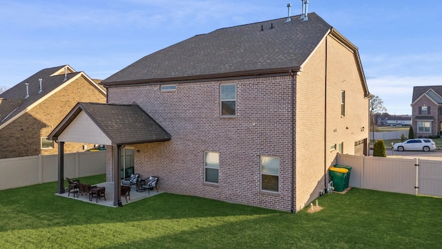 back of house with a patio, a fenced backyard, brick siding, a yard, and roof with shingles