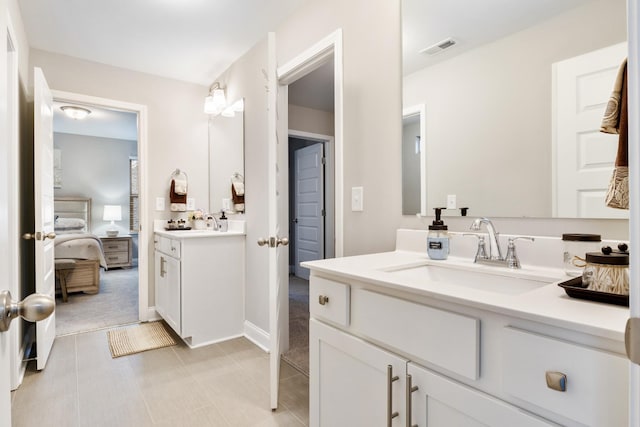 full bath featuring two vanities, visible vents, connected bathroom, and a sink