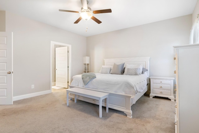 bedroom featuring baseboards, ceiling fan, ensuite bathroom, and light colored carpet