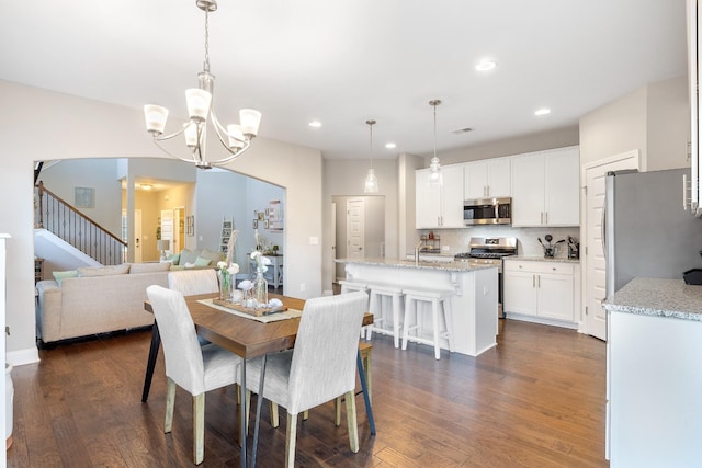 dining area featuring stairs, dark wood-style flooring, an inviting chandelier, and recessed lighting