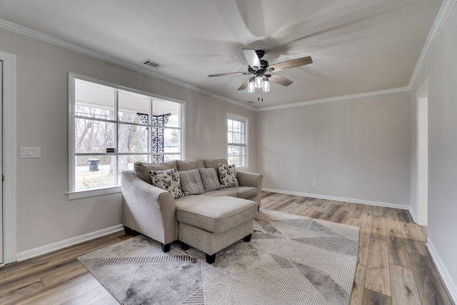 living area with baseboards, wood finished floors, and crown molding