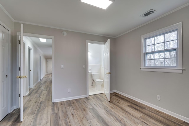 unfurnished bedroom featuring ornamental molding, light wood-type flooring, visible vents, and baseboards