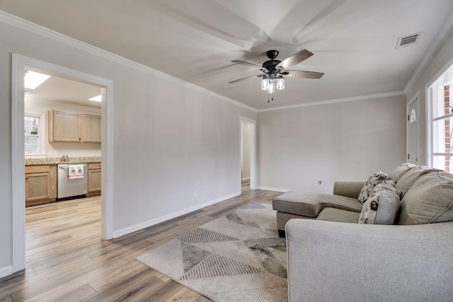 living room with light wood finished floors, visible vents, a ceiling fan, and ornamental molding