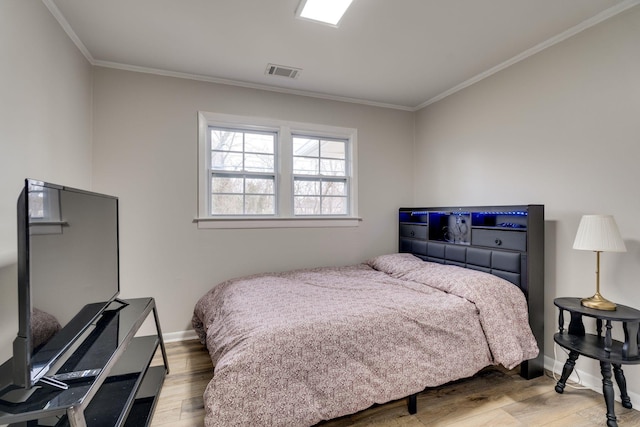 bedroom with baseboards, visible vents, wood finished floors, and ornamental molding