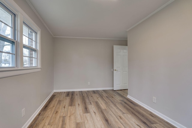 empty room with ornamental molding, light wood-type flooring, and baseboards