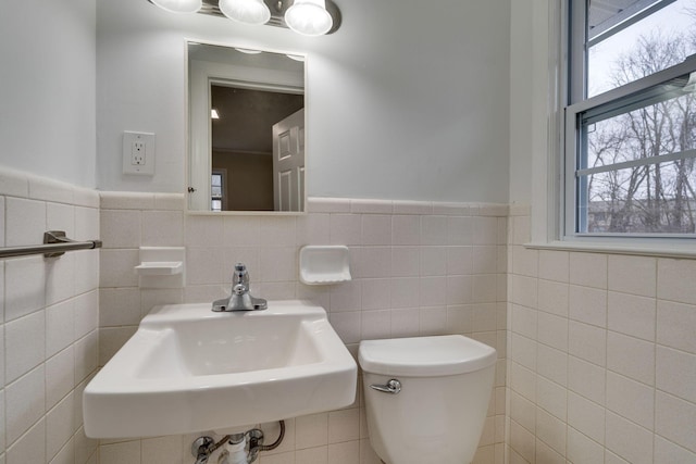 half bath featuring a wainscoted wall, a sink, and toilet