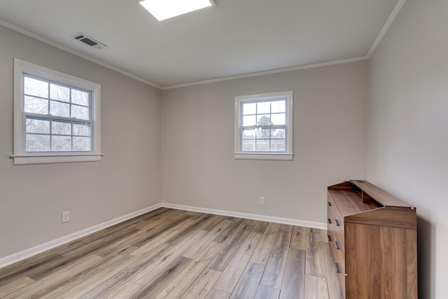 empty room featuring light wood finished floors, baseboards, visible vents, and ornamental molding