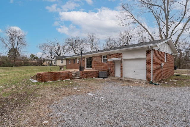 ranch-style home featuring a garage, driveway, brick siding, cooling unit, and a front yard