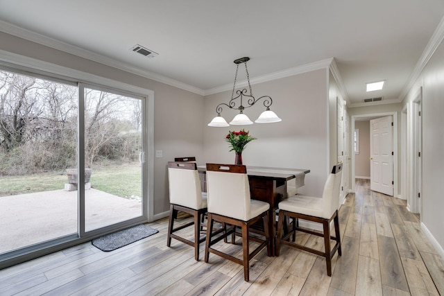 dining room featuring light wood-style floors, visible vents, and ornamental molding