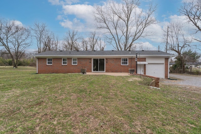 back of property featuring a patio, an attached garage, brick siding, a yard, and gravel driveway