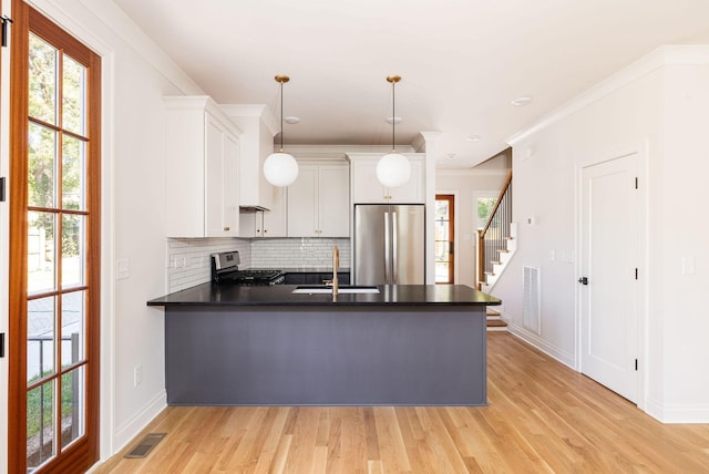 kitchen with stainless steel appliances, a peninsula, visible vents, white cabinetry, and decorative light fixtures