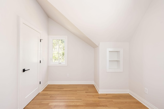 bonus room with built in features, vaulted ceiling, light wood-style flooring, and baseboards