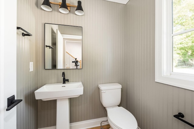 half bathroom with baseboards, a sink, and toilet