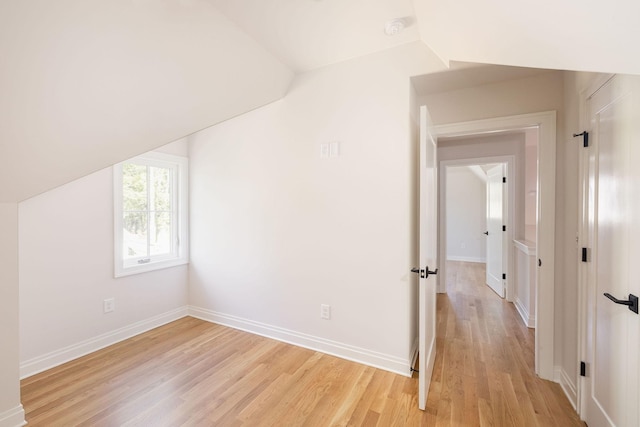 bonus room with light wood-type flooring, lofted ceiling, and baseboards