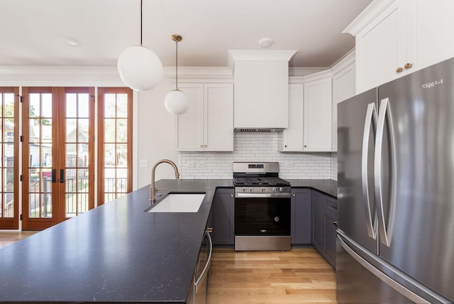 kitchen featuring a sink, white cabinetry, hanging light fixtures, appliances with stainless steel finishes, and tasteful backsplash