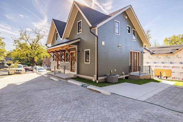 rear view of property featuring central AC and a shingled roof