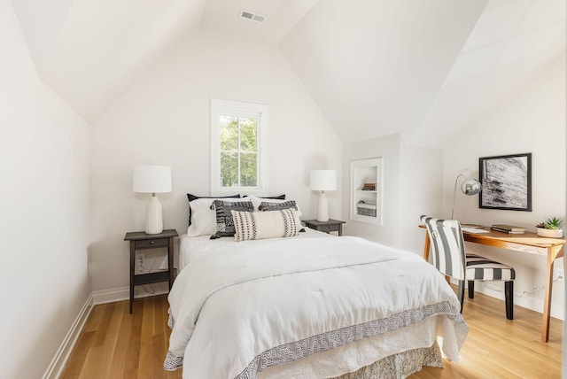 bedroom with lofted ceiling, baseboards, visible vents, and wood finished floors