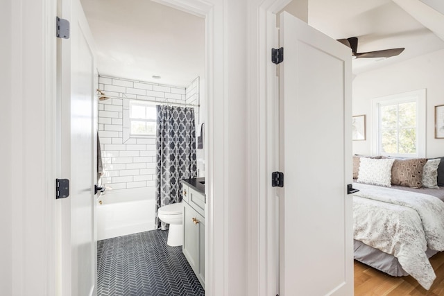 ensuite bathroom with shower / bath combo, a ceiling fan, toilet, ensuite bath, and vanity