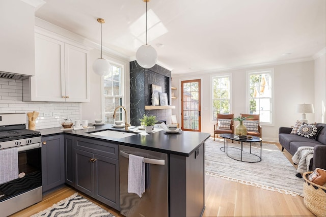 kitchen with dark countertops, appliances with stainless steel finishes, white cabinetry, a sink, and a peninsula