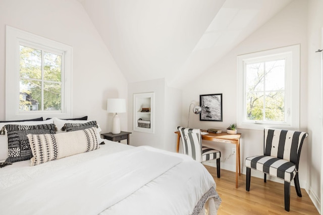 bedroom with lofted ceiling, multiple windows, and light wood finished floors