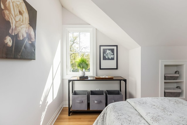 bedroom with lofted ceiling, baseboards, and wood finished floors