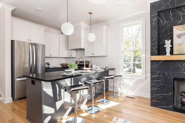 kitchen featuring tasteful backsplash, white cabinets, dark countertops, freestanding refrigerator, and pendant lighting