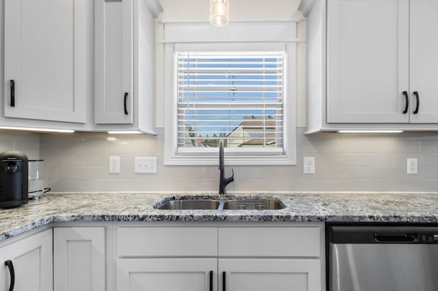 kitchen with stainless steel dishwasher, a sink, backsplash, and light stone countertops