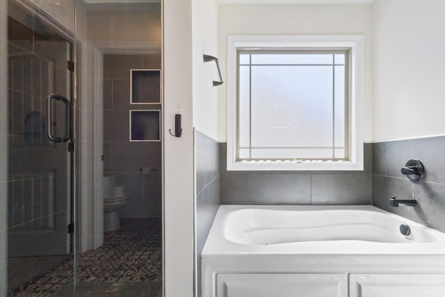 full bathroom with a stall shower, a garden tub, toilet, tile walls, and wainscoting