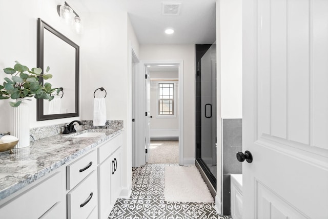 bathroom featuring a shower stall, double vanity, baseboards, tile patterned floors, and recessed lighting