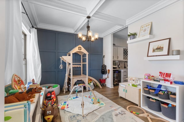 recreation room featuring beverage cooler, ornamental molding, coffered ceiling, dark wood-style flooring, and a decorative wall