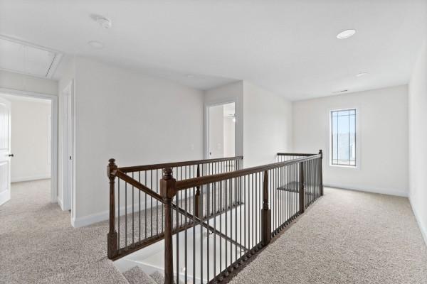 hallway featuring attic access, carpet flooring, an upstairs landing, and baseboards