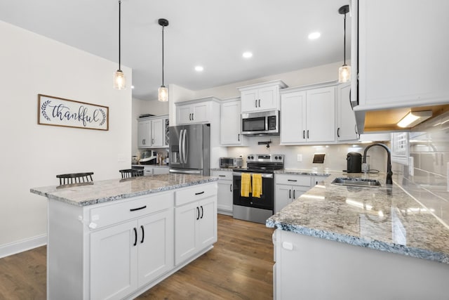 kitchen with stainless steel appliances, a sink, dark wood-type flooring, tasteful backsplash, and white cabinetry