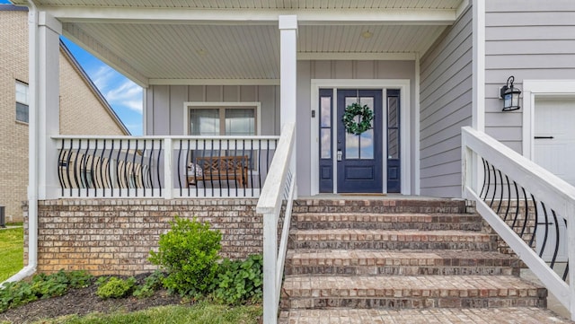 entrance to property with a porch, board and batten siding, and central AC