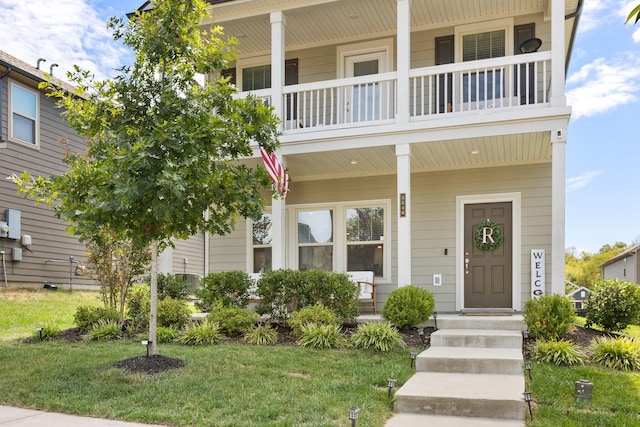 view of front facade featuring covered porch, a front lawn, and a balcony