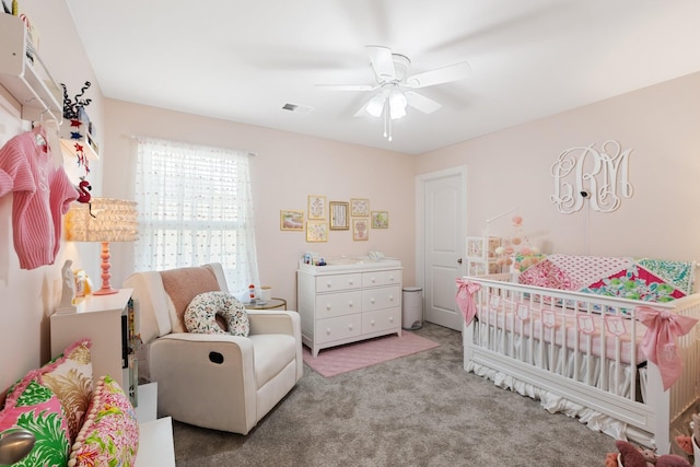 bedroom with a crib, ceiling fan, visible vents, and carpet flooring