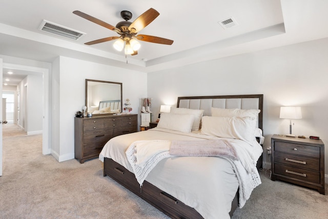 bedroom featuring light carpet, a raised ceiling, and visible vents