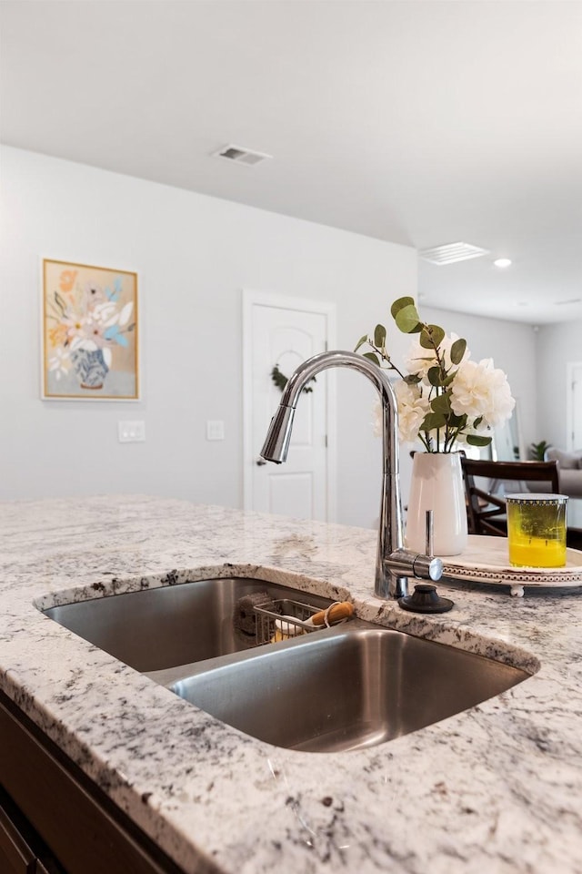 details with light stone counters, a sink, and visible vents