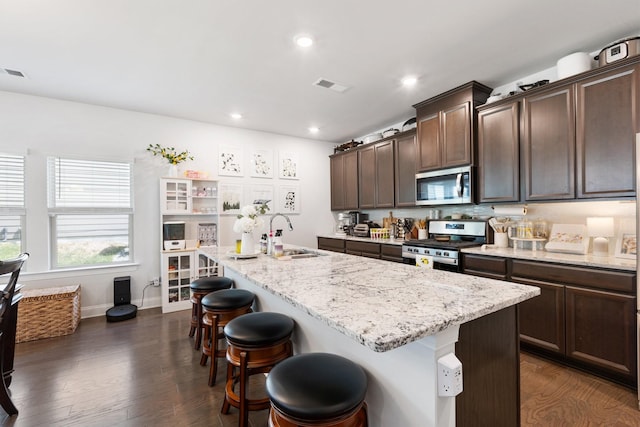 kitchen featuring stainless steel appliances, an island with sink, a sink, and visible vents