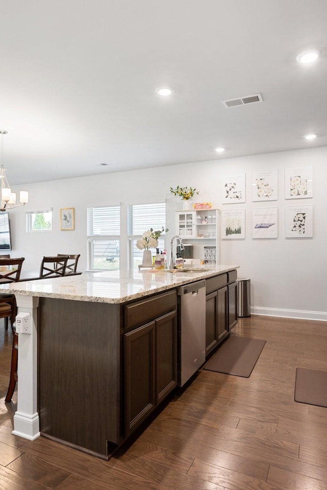 kitchen featuring visible vents, an island with sink, a kitchen bar, pendant lighting, and stainless steel dishwasher