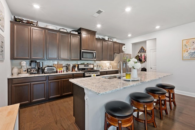 kitchen with stainless steel appliances, a kitchen bar, a sink, and a kitchen island with sink