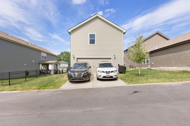 view of front of home featuring an attached garage, fence, a front lawn, and concrete driveway