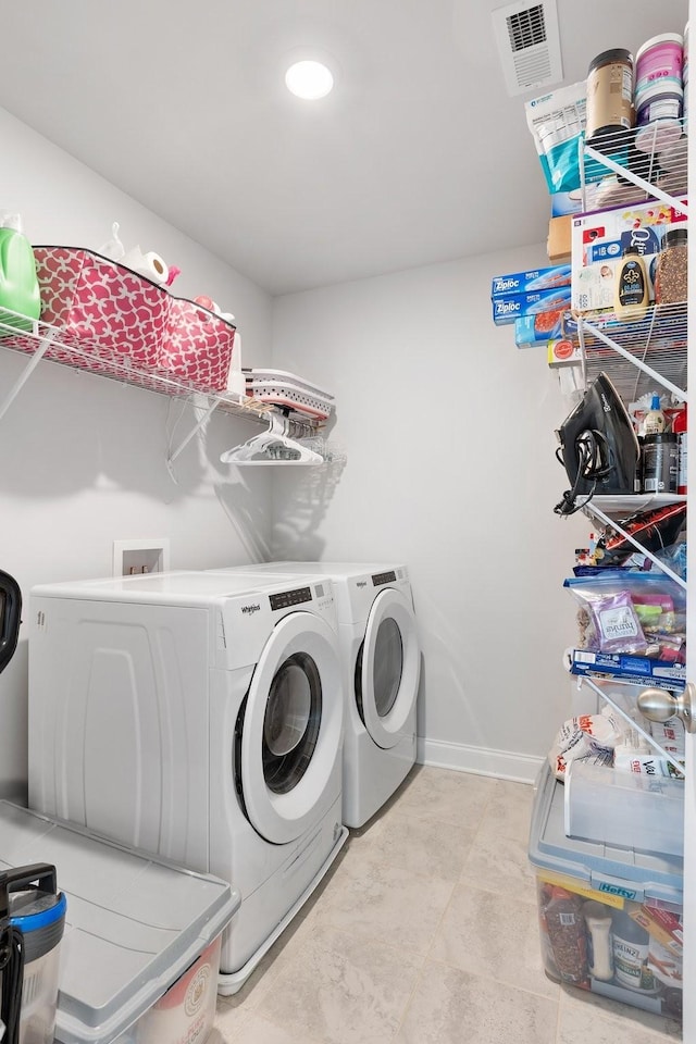 laundry area with laundry area, separate washer and dryer, visible vents, and baseboards