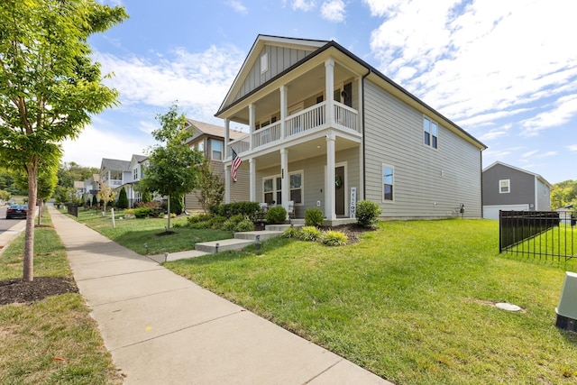 view of front of home featuring a porch, board and batten siding, a front yard, fence, and a balcony