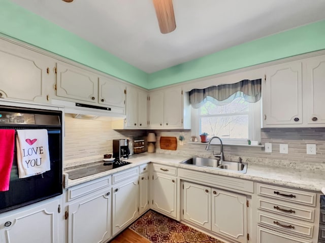 kitchen with light countertops, black appliances, a sink, and under cabinet range hood