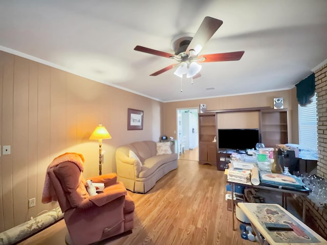 living area featuring light wood-style flooring, ornamental molding, and a ceiling fan