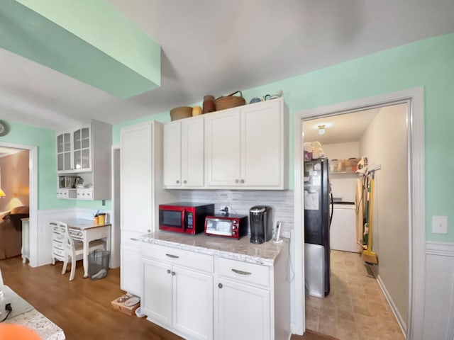 kitchen with light stone counters, freestanding refrigerator, white cabinetry, and open shelves